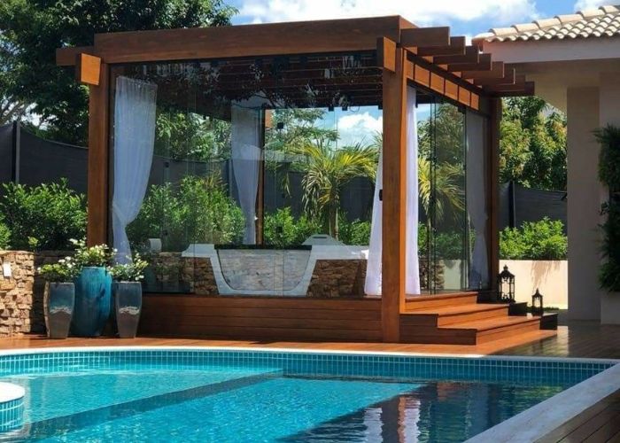 pergolado de madeira de vidro sofisticado ao lado da piscina